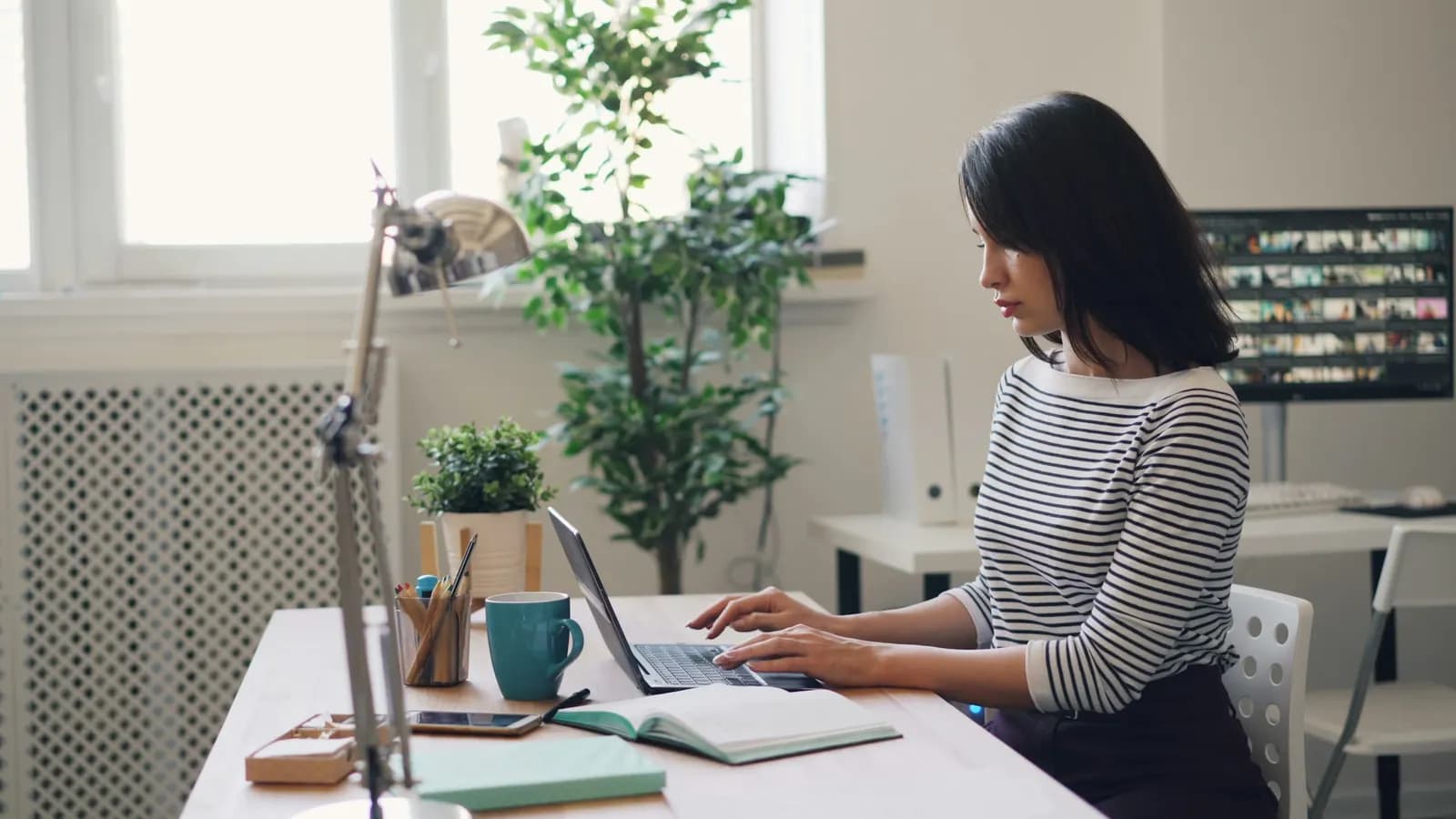 Person working at a laptop at a bright home-office desk