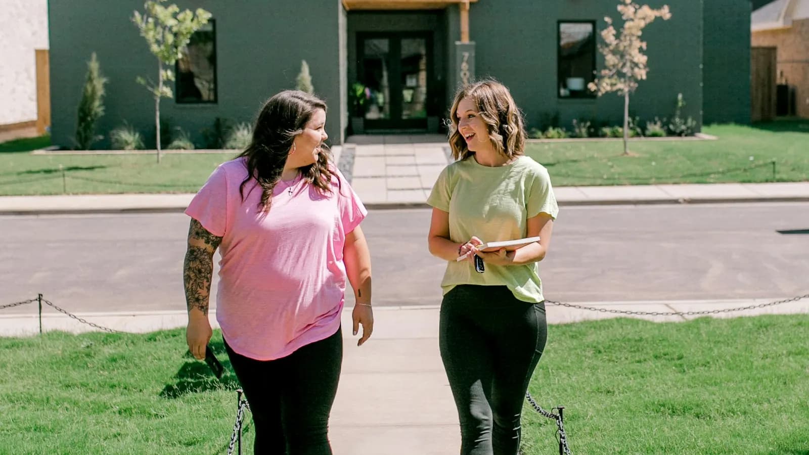Two sales reps with a notebook walking a suburban neighborhood sidewalk