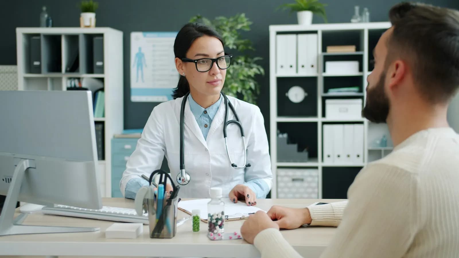 Clinician talking with a patient across a desk in a bright medical office