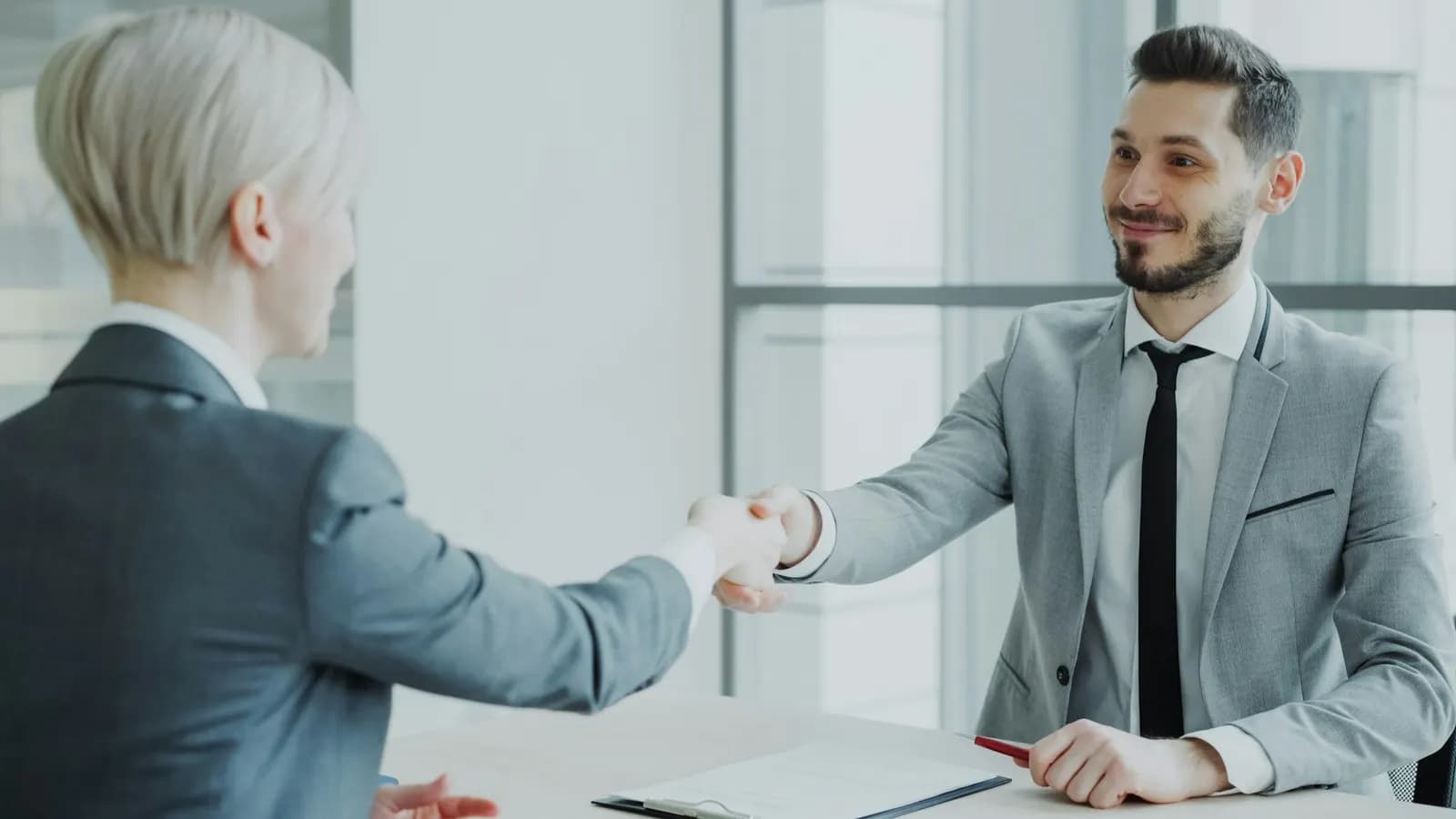 Manager shaking hands with a new team member in a bright office