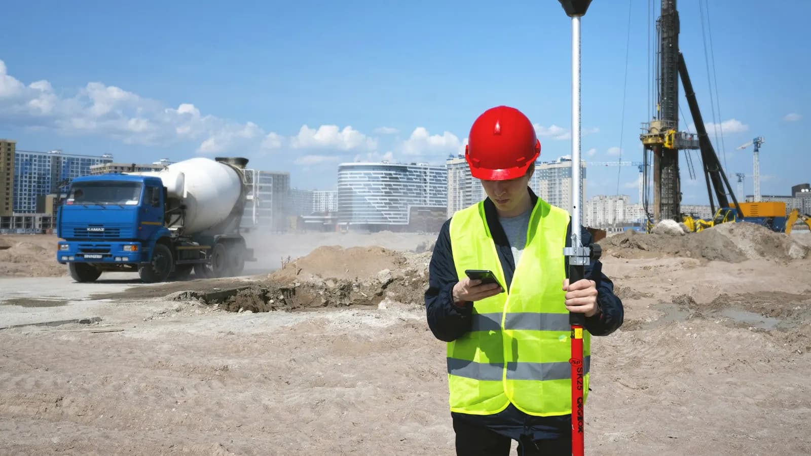 Site surveyor checking a phone on a construction site