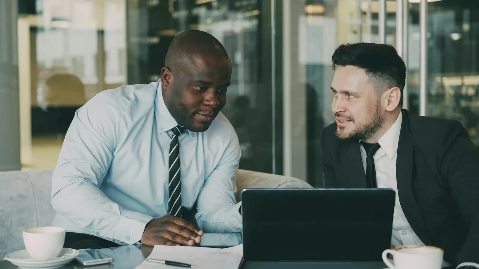 Two business colleagues discussing a proposal on a tablet at a table