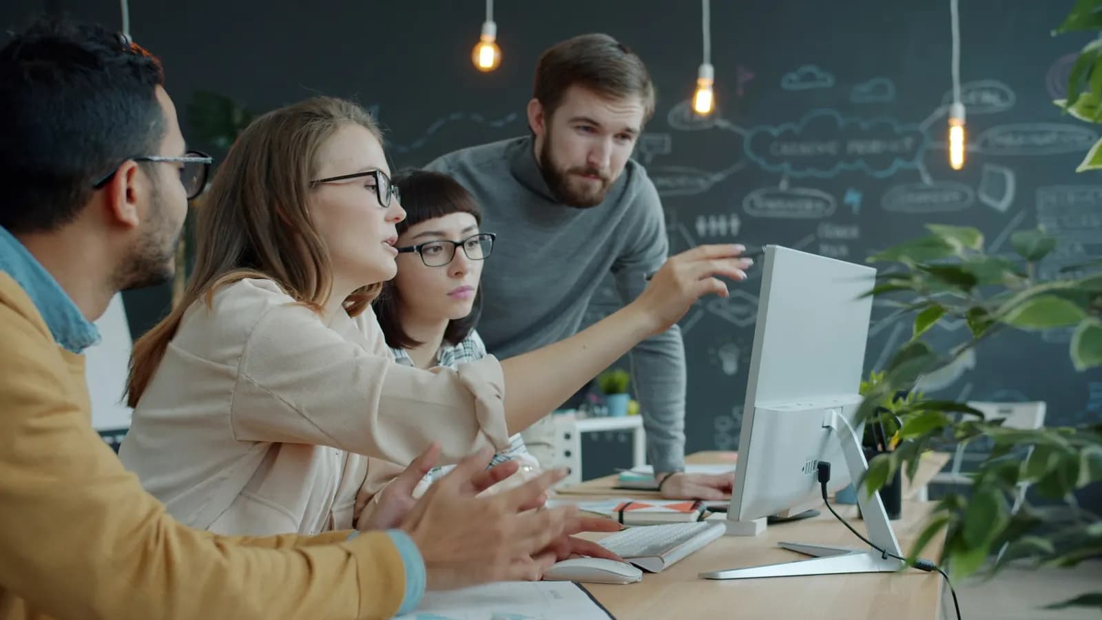 Colleagues pointing at a monitor while planning together in an office