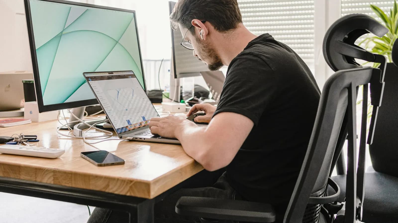 Web designer working on a site layout at a desk with two screens